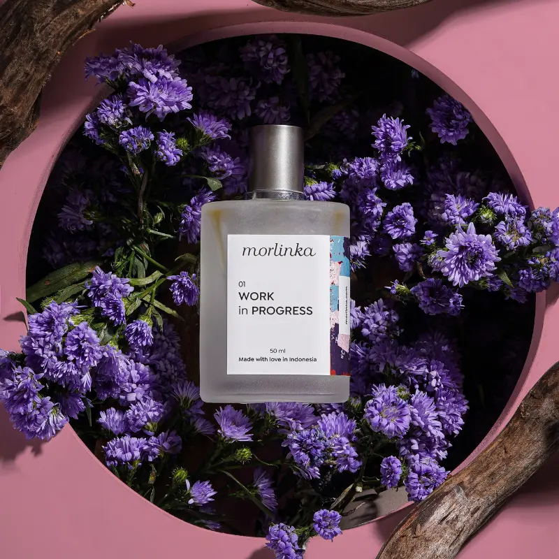 Morlinka “Work in Progress” crystal mist placed among vibrant purple flowers, highlighting its fresh and calming design.